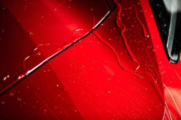 Turtle Wax treated red car surface gleams. Water beads show deep shine. Auto detailing finish. #cardetailing #autocare #TurtleWax
