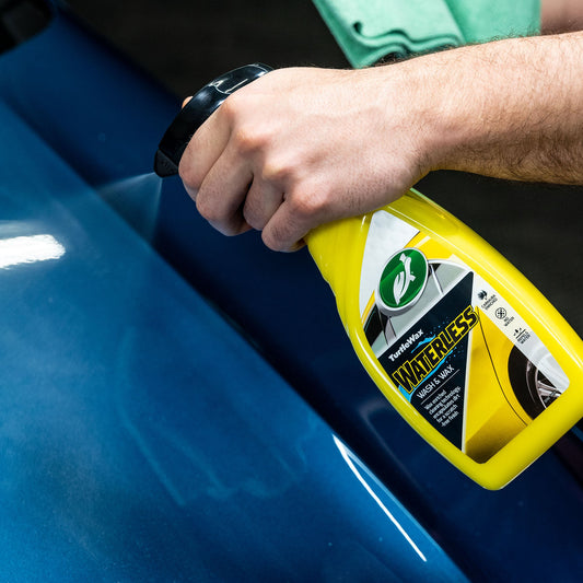 Hand spraying Turtle Wax waterless wash & wax. Easy car cleaning, no water needed. Car care for shine and protection.