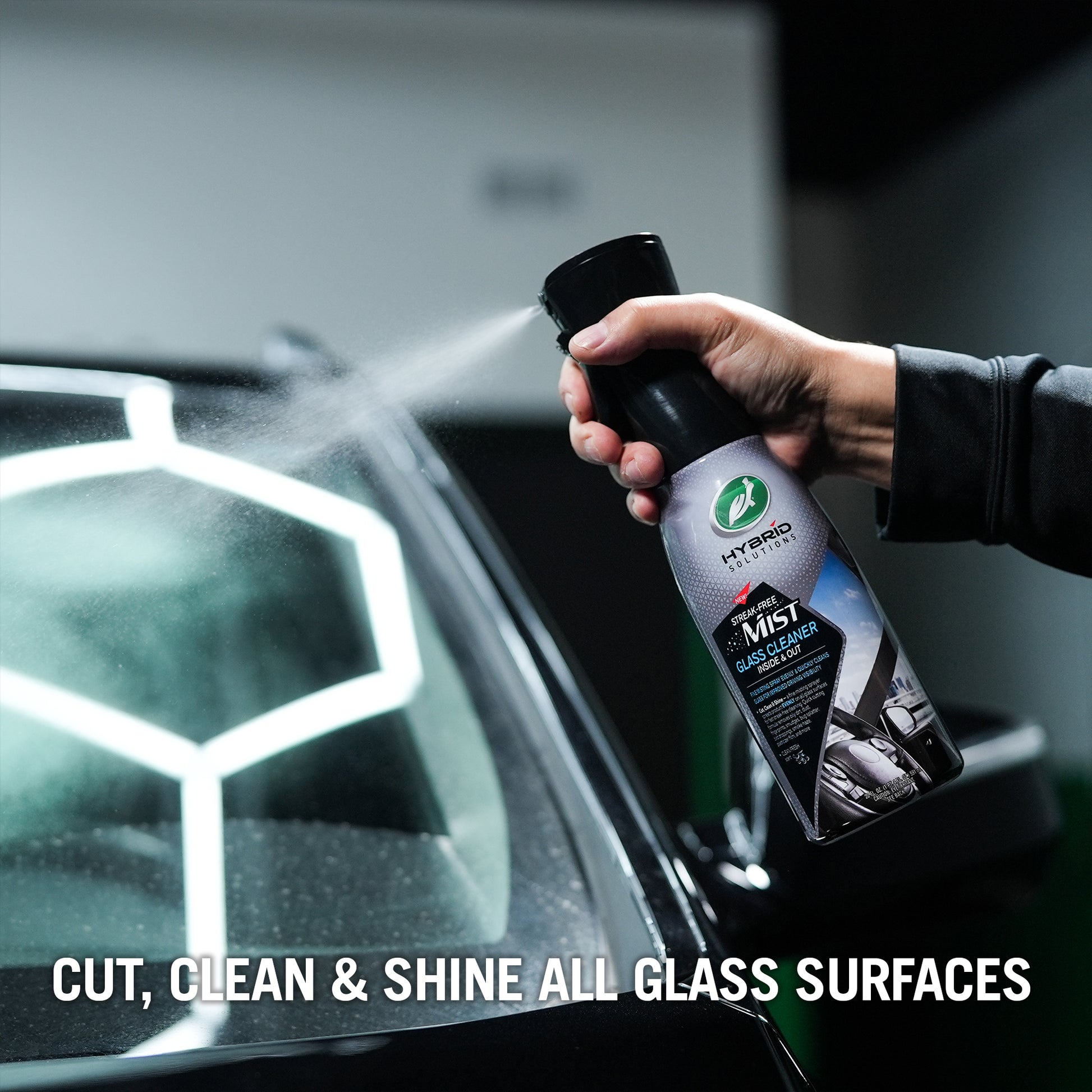 Hand spraying Turtle Wax Hybrid Solutions glass cleaner on car windshield for streak-free visibility. कार की सफाई.
