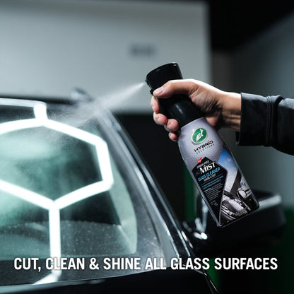 Hand spraying Turtle Wax Hybrid Solutions glass cleaner on car windshield for streak-free visibility. कार की सफाई.
