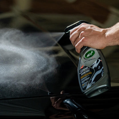Turtle Wax Hybrid Solutions Ceramic Acrylic Black Wax being sprayed on a black vehicle. Car care product application.