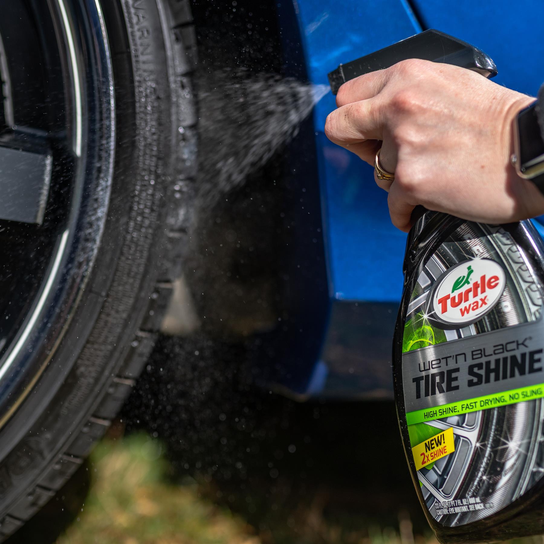 Turtle Wax Wet'n Black tyre shine being sprayed on car tyre, for a high shine finish.