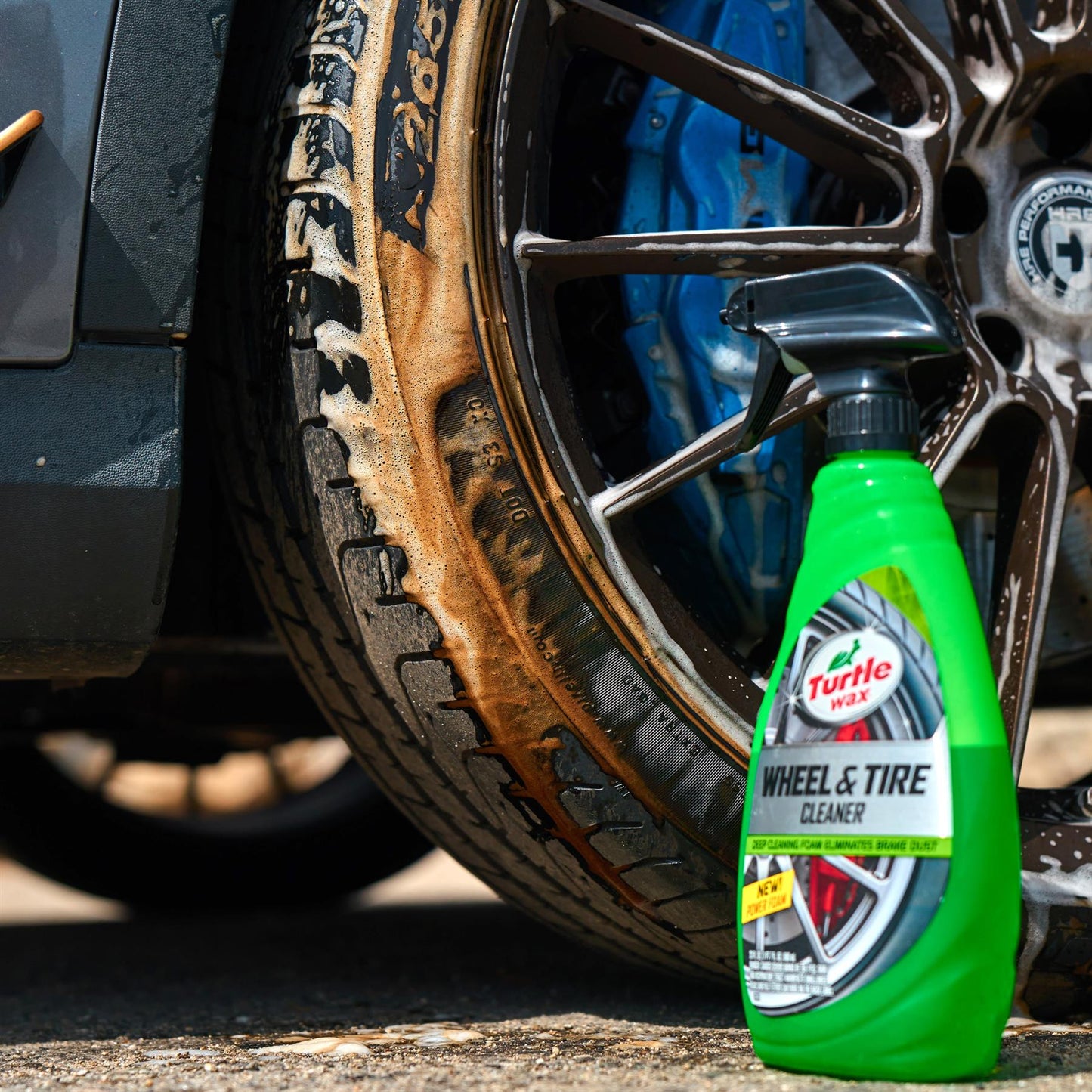 Dirty car wheel and tire covered in foam cleaner. Turtle Wax Wheel & Tire Cleaner spray bottle displayed, auto detailing, India.
