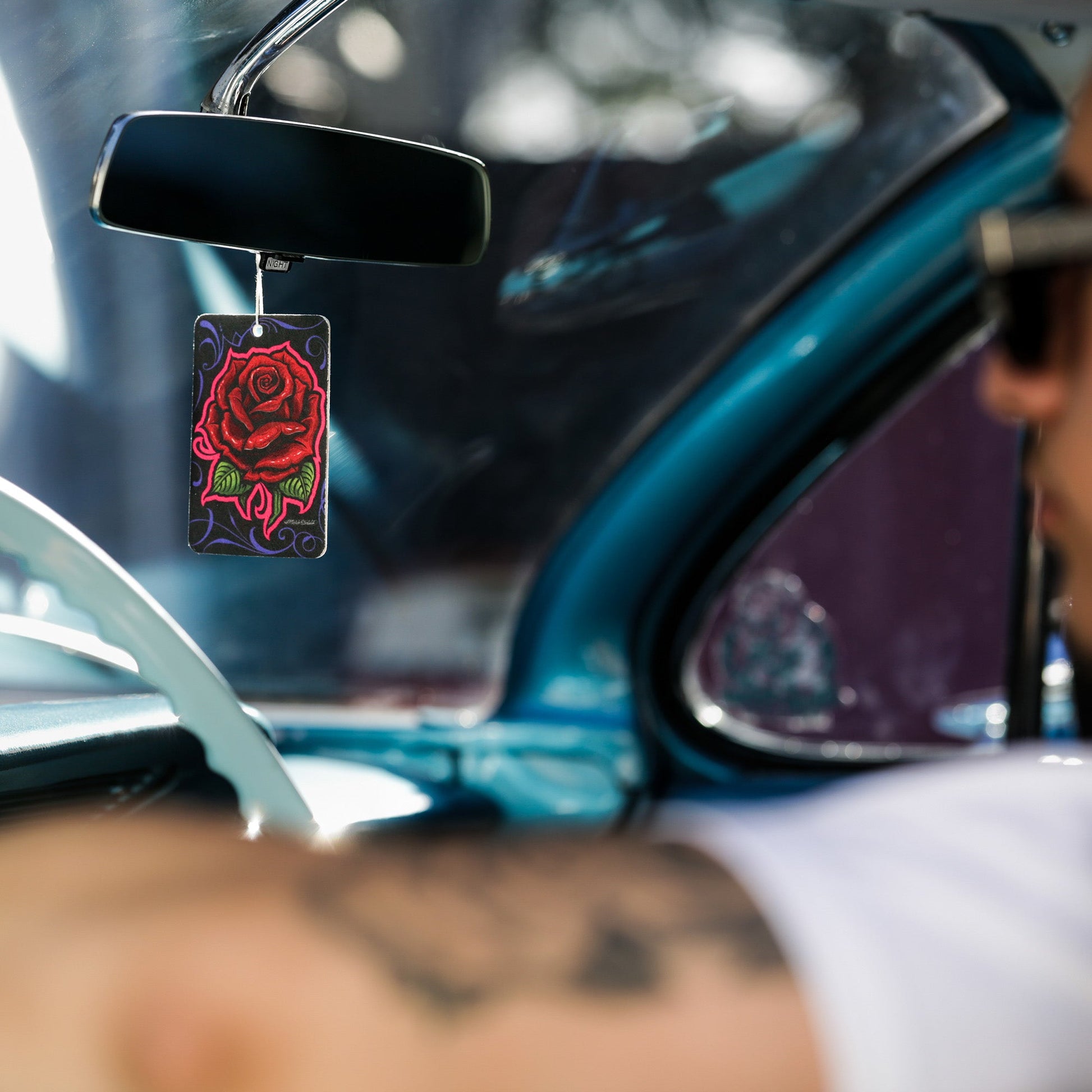 Car interior with rose-themed paper hanging from the rearview. Auto style for India.
