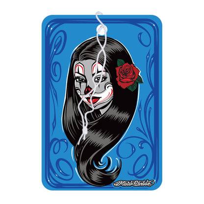 Blue air freshener featuring a woman's face with clown makeup and a rose. India themed.