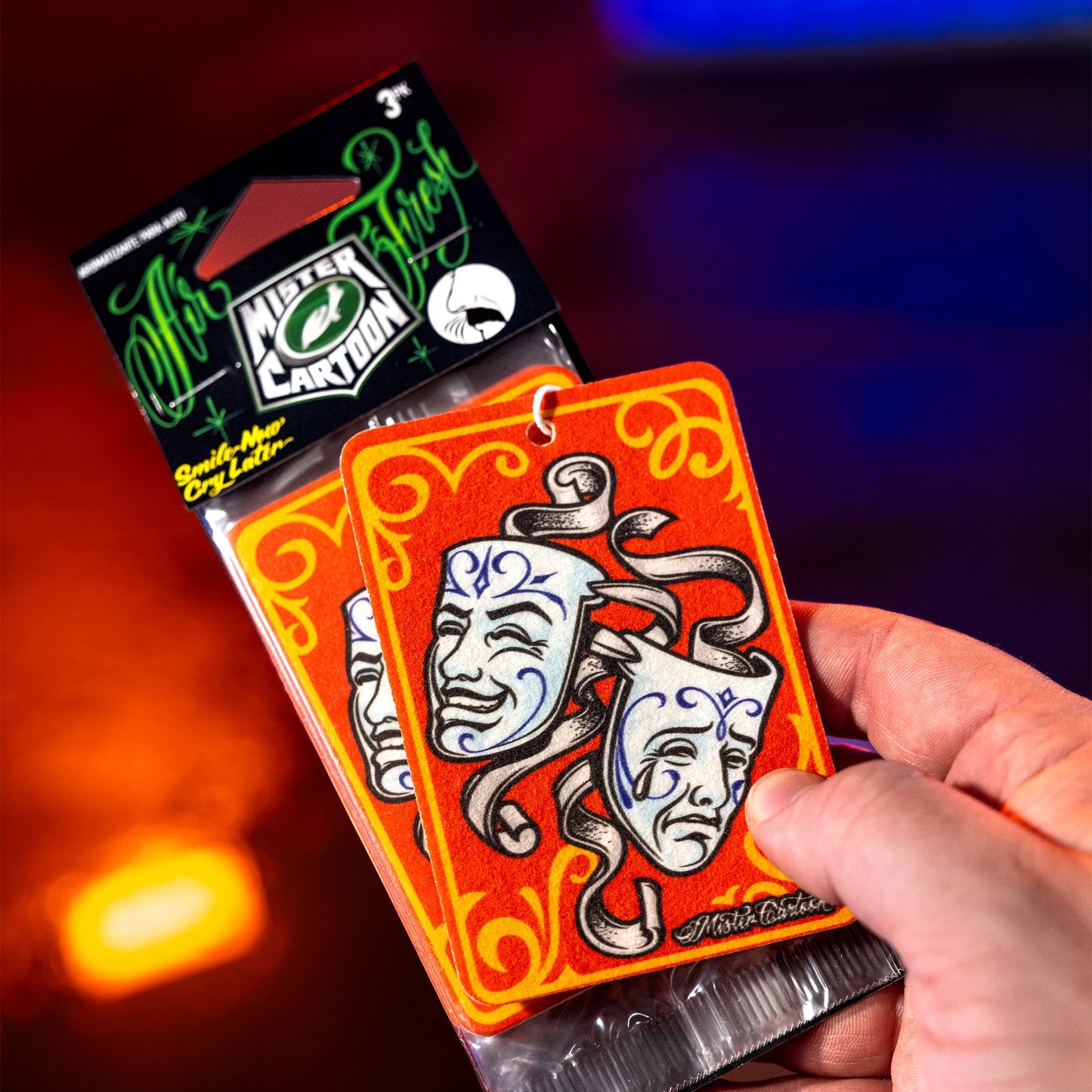 Smile Now Cry Later paper air fresheners in hand. Theater masks art. Car fragrance.