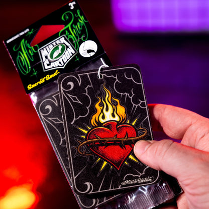 Hand holds Mister Cartoon Sacred Soul air freshener. Flaming heart design. Car accessories for Indian drivers.