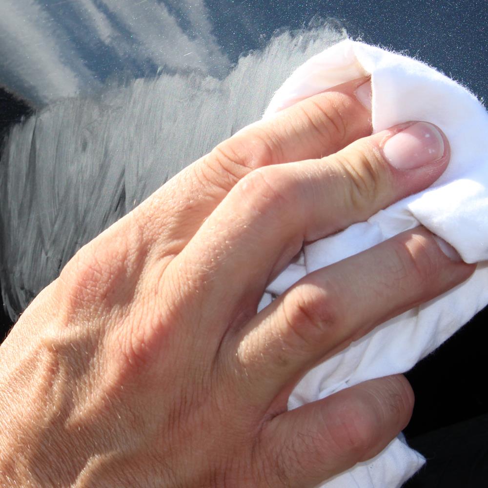 Hand applies Turtle Wax scratch remover to a car surface, using a cloth for polishing.