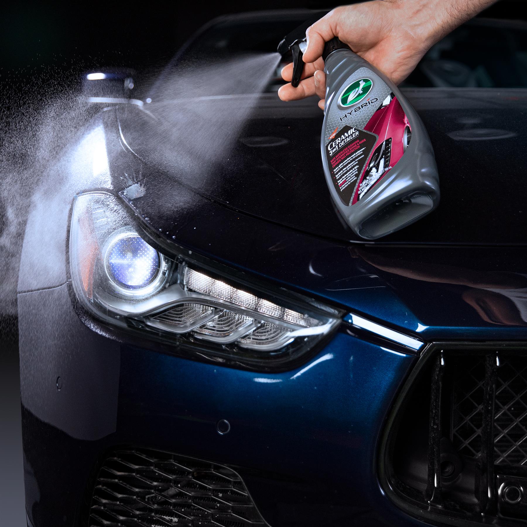 Turtle Wax Hybrid Solutions Ceramic 3-in-1 Detailer being sprayed on a blue car, close-up of the headlight.