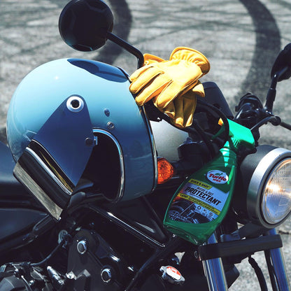 Turtle Wax protectant spray atop a motorcycle near a helmet and gloves, great for bike care in India.