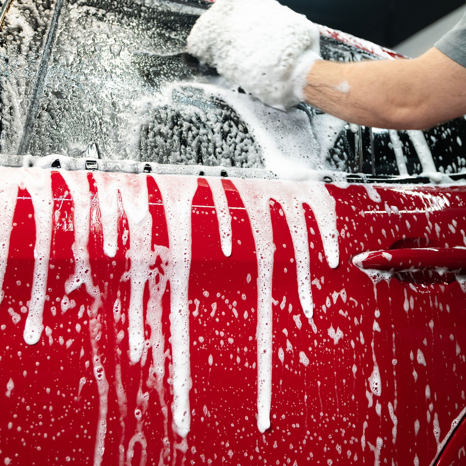Red car getting washed with Turtle Wax foam. Auto detailing for a sparkling finish.