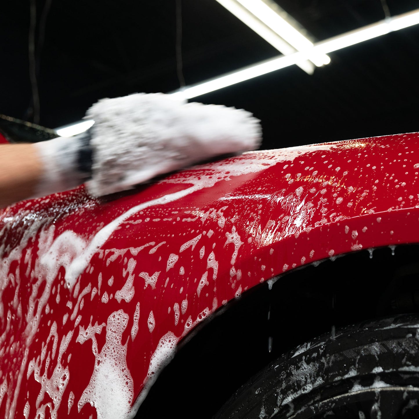 Red car being washed with a foamy mitt. Car detailing for a shiny, clean finish. Turtle Wax quality for auto care.