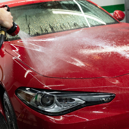 Red car wash: Red car being sprayed with water. Turtle Wax products can help clean and protect your car. #carwash #cardetailing #india
