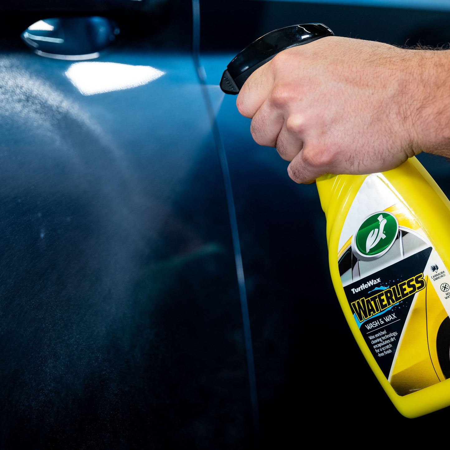 Turtle Wax waterless car cleaner is sprayed for wax coating on a dark blue car.