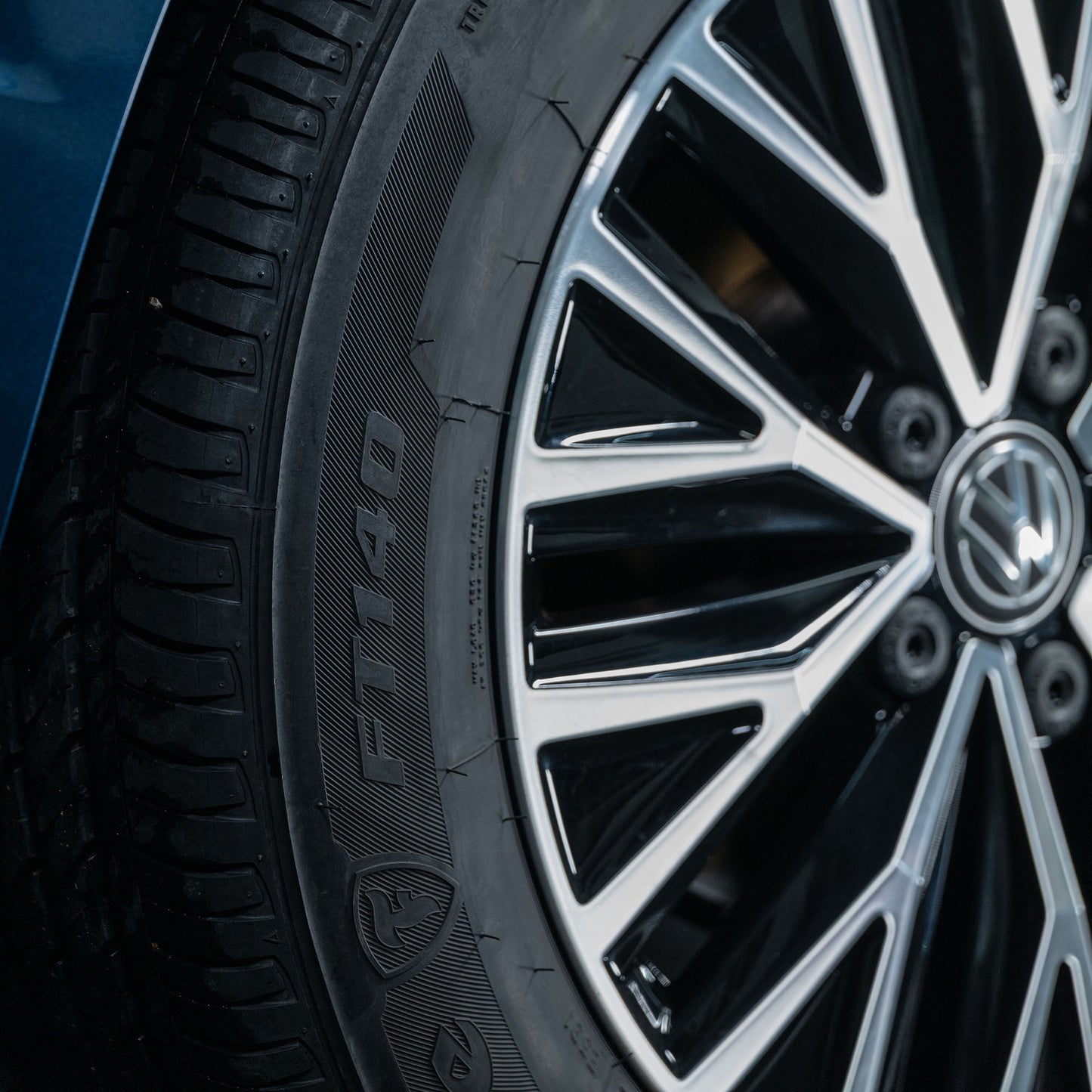 Close-up of a car tyre showing its tread pattern and an alloy wheel with the Volkswagen logo at the center.