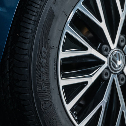 Close-up of a car tyre showing its tread pattern and an alloy wheel with the Volkswagen logo at the center.