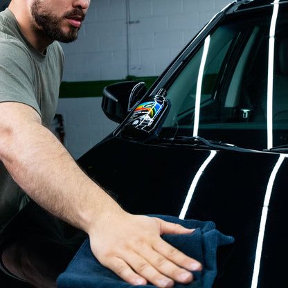 Man applies Turtle Wax Color Magic Black to a shiny car. Car care for black vehicles.