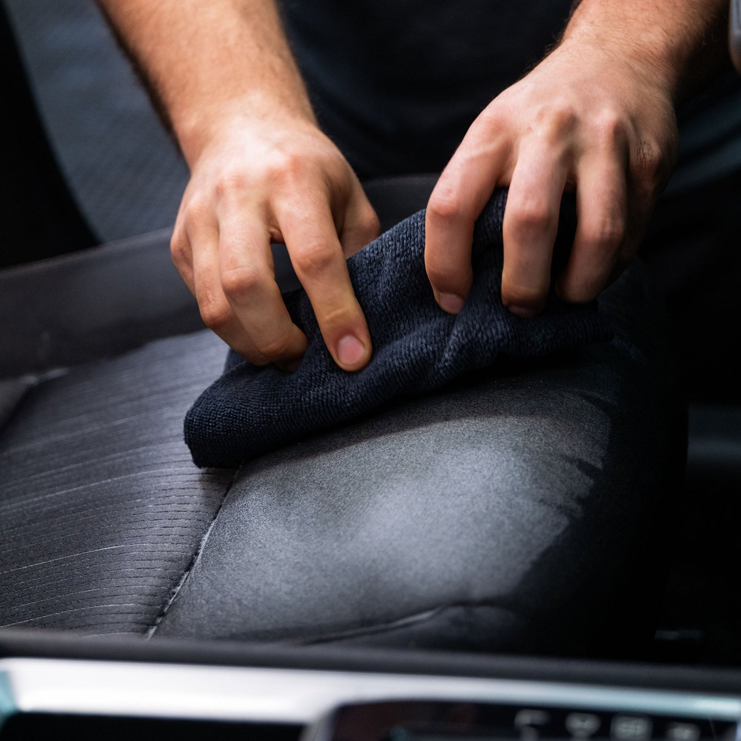 Hands cleaning car seat upholstery with a cloth. Interior detailing. Turtle Wax cleaning products.