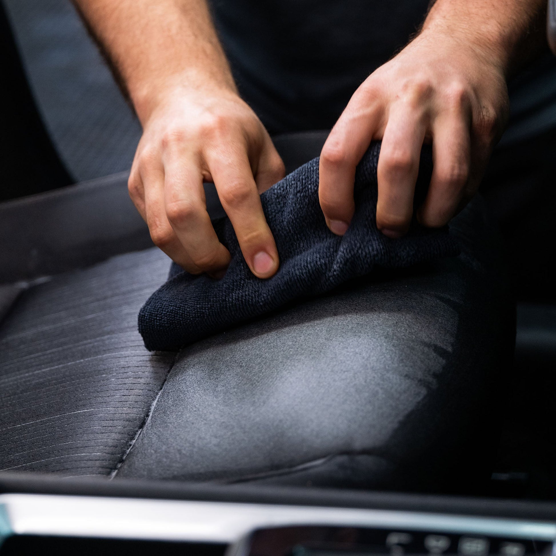 Hands cleaning car seat upholstery with a cloth. Interior detailing. Turtle Wax cleaning products.