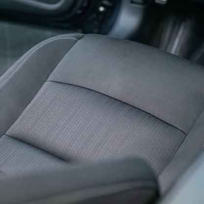 Car seat featuring fabric in a dark tone, showcasing detailing like stitching.
