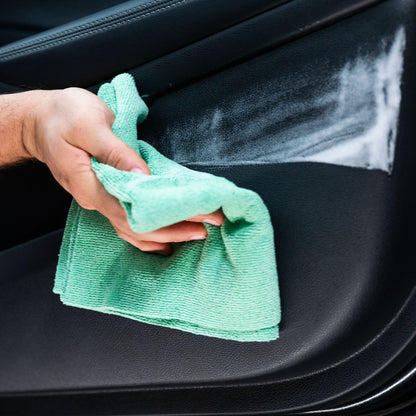 Car interior cleaning: A microfiber cloth wipes dirt from the door panel.

