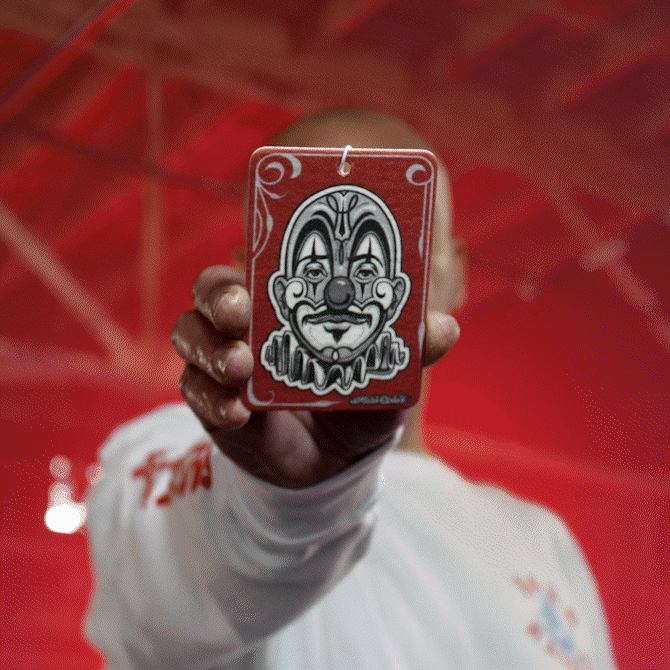 Man holds air freshener with clown design. Auto accessories for car interior in India.
