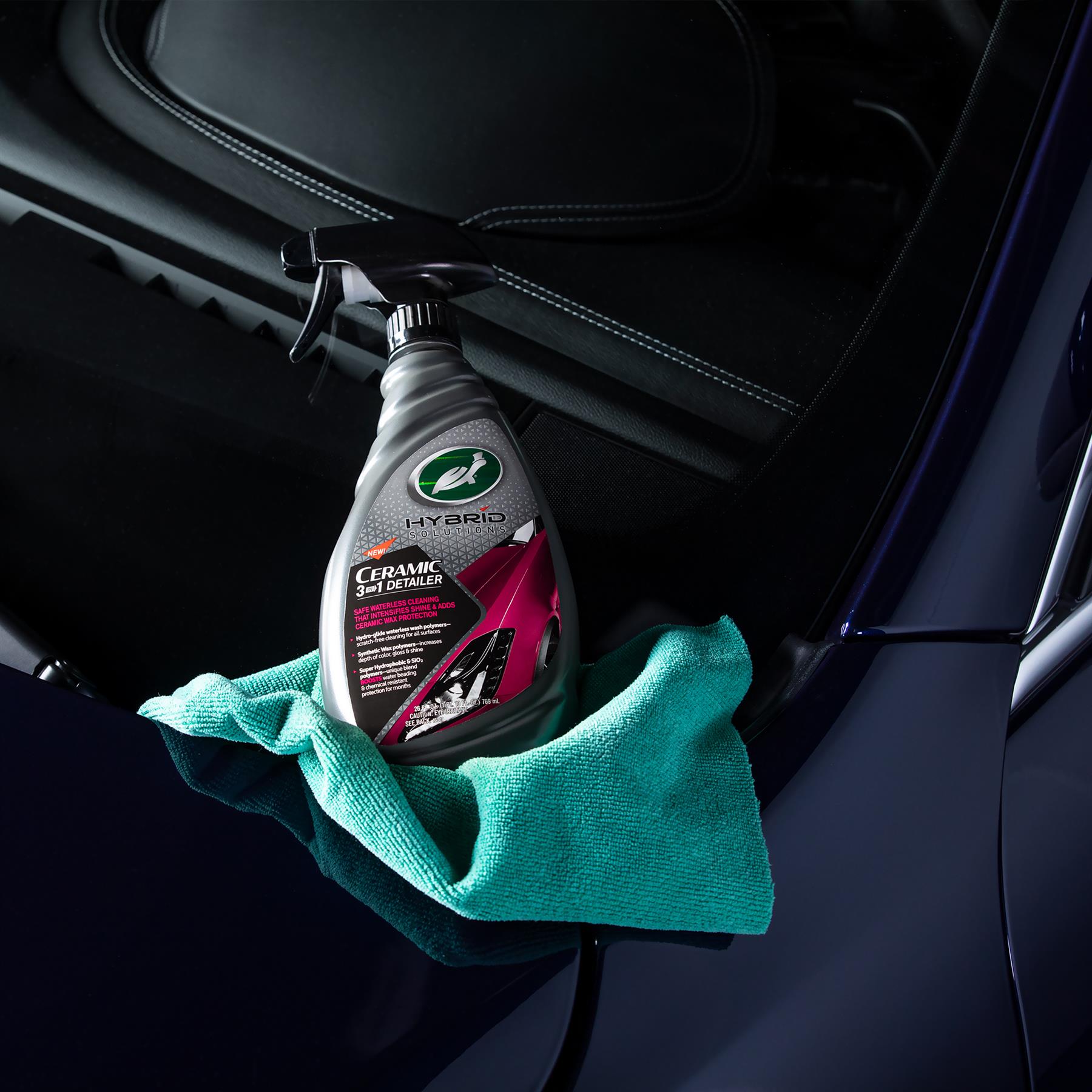 Turtle Wax Hybrid Solutions Ceramic 3-in-1 Detailer (946ml) with microfibre cloth on a shiny blue car's hood, for car detailing.