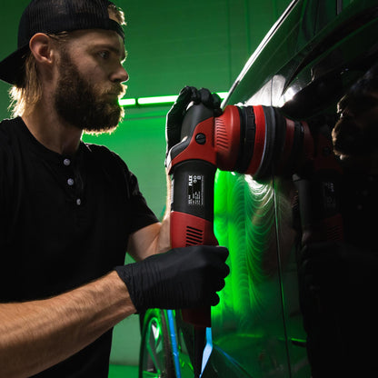 Auto detailer using a machine buffer on a car panel. Swirl marks visible. Car care in India.