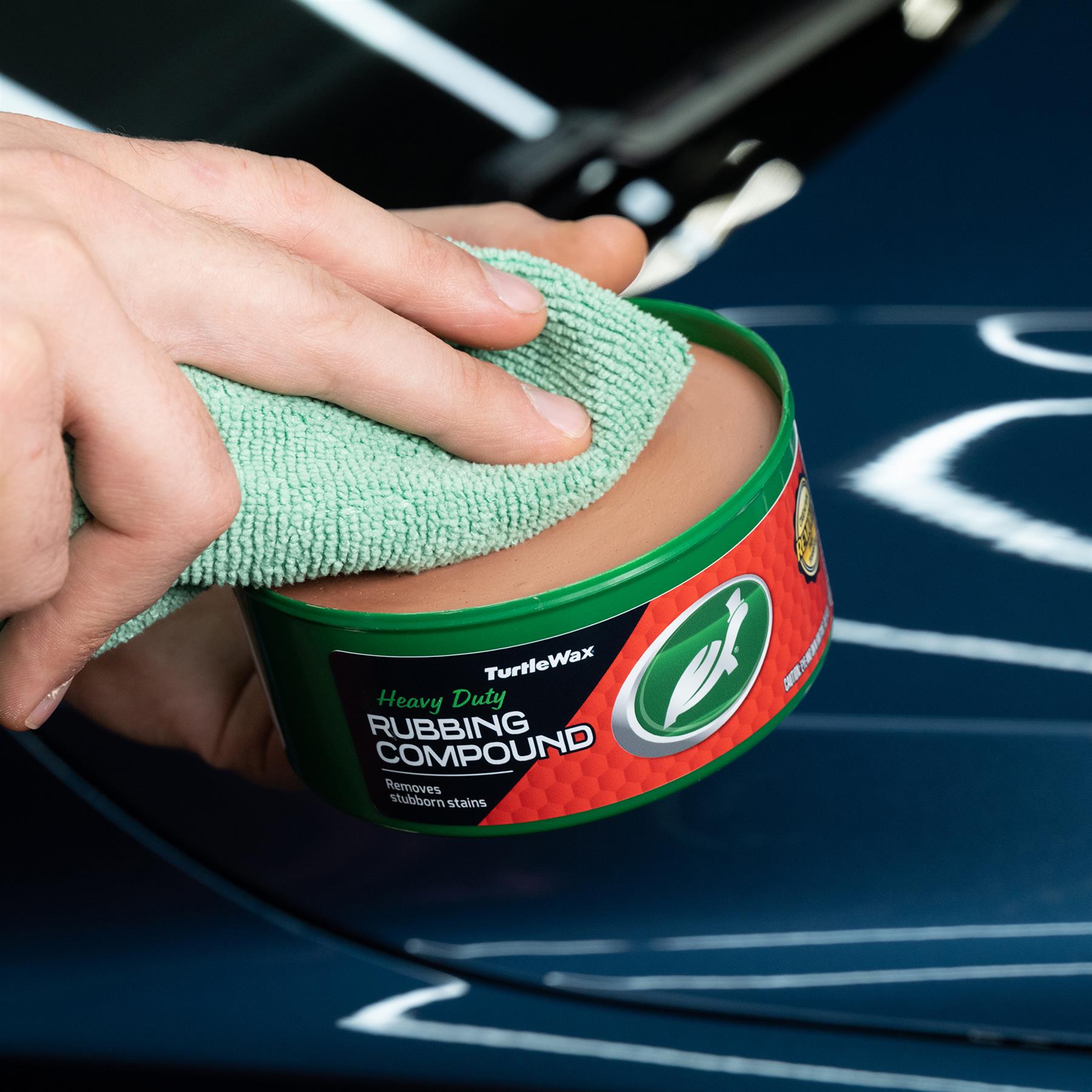 Turtle Wax Heavy Duty Rubbing Compound (298gm) being applied on a car with a green cloth.
